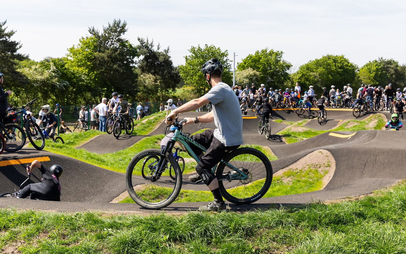 A busy Kesgrave Pump Track with teens on bikes during its opening ceremony
